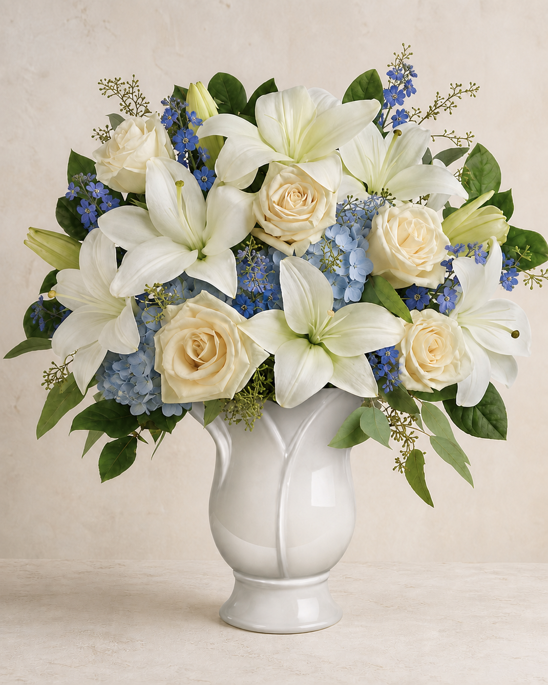 Natural powder-blue flowers with cream-white lilies and ivory roses in a ceramic vase
